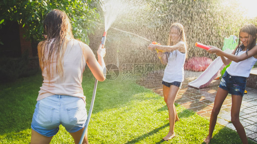 在炎热的夏日里孩子们拿着水和花园水龙带开心地笑着和孩子们在一起夏天一家人在户外玩耍和娱乐图片