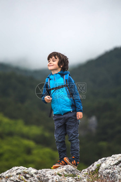 一个背着背包的男孩站在山顶上图片