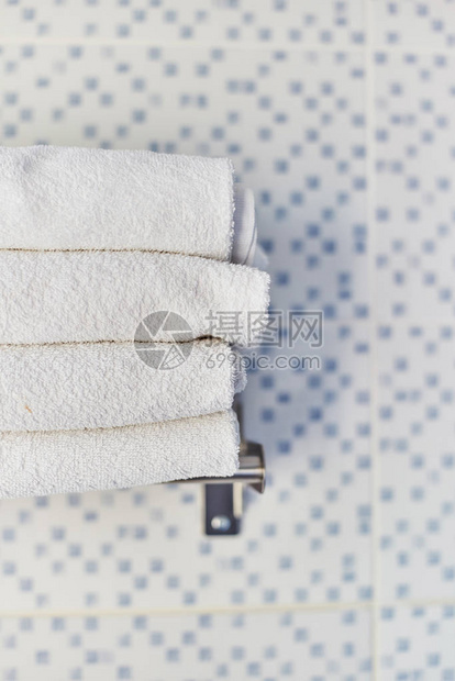 一堆白色干净的毛巾在旅馆房间里酒店洗手间的架子图片
