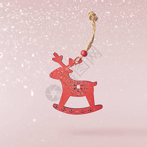 圣诞贺卡概念圣诞玩具鹿装饰在粉红背景的空气中坠落升华概念图片
