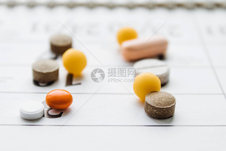 一堆不同的药丸在日历背景上治疗该疾病的药丸补充剂和药高清图片下载-正版图片507478176-摄图网