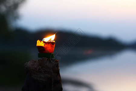 燃着热火的蜡烛在模糊黑暗的黑滨河岸反射波浪背景下闪亮地燃烧背景图片
