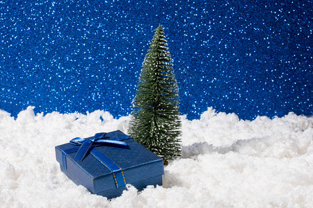 圣诞树下面的礼物盒在白雪上图片