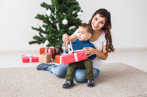 圣诞节单亲家庭和假日概念可爱的小男孩拿着圣诞礼物给他的母亲在家图片