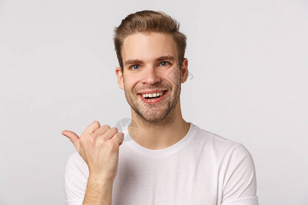 特写摄影棚肖像金发帅气快乐微笑的男士向请教意见拇指左指讨论公司产品笑容开朗站在白色背景下背景图片
