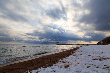 冬季海滩蓝色清澈的海水沙地上的雪地平线和山丘图片