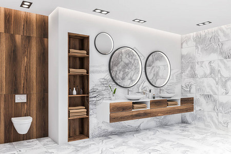 豪华主浴室的角落有白色大理石墙壁带两个圆形镜子的双水槽和靠近带毛巾的深色木架子的厕所图片