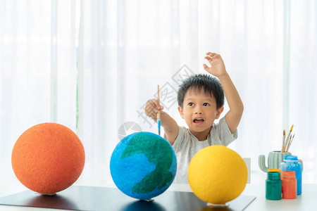 亚洲学龄前男孩画月亮在家学习太阳系在家上背景图片