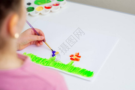 小女孩的手在绿草上画花用白纸上的图片