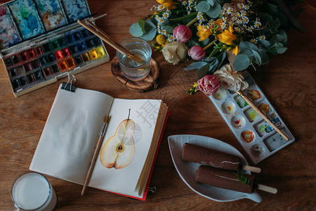 艺术家的桌面有水彩调色板素描本永生春花束绘画用品牛奶图片