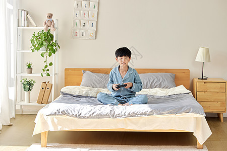 在床上玩游戏的男孩背景图片