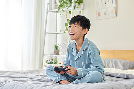 在床上玩游戏的男孩图片