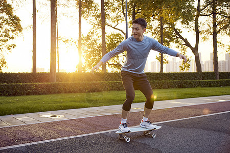 夕阳下男青年玩滑陆冲板图片