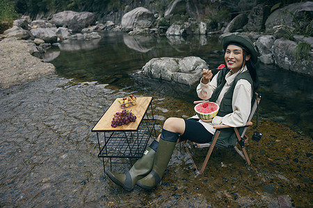 年轻美女溪边露营旅行享受水果图片