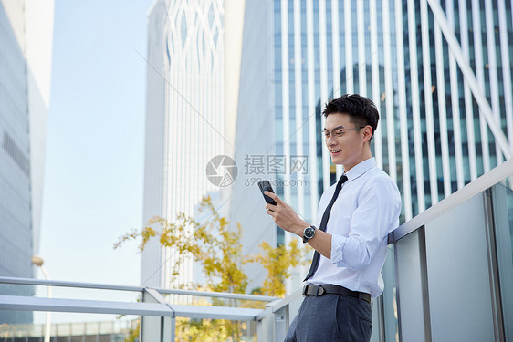 户外玩手机的商务男士形象图片