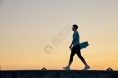 夕阳下男青年拿着滑板剪影图片