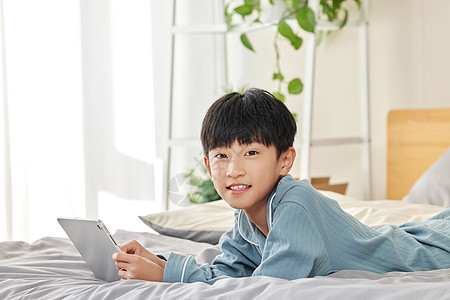 在床上玩平板电脑的小男孩图片