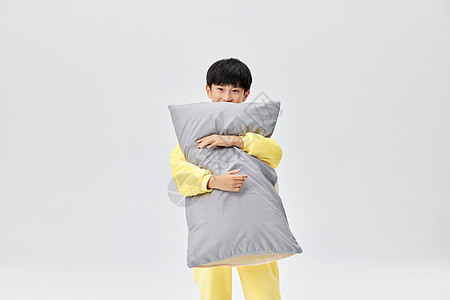 穿着居家睡衣抱枕头的小男孩图片