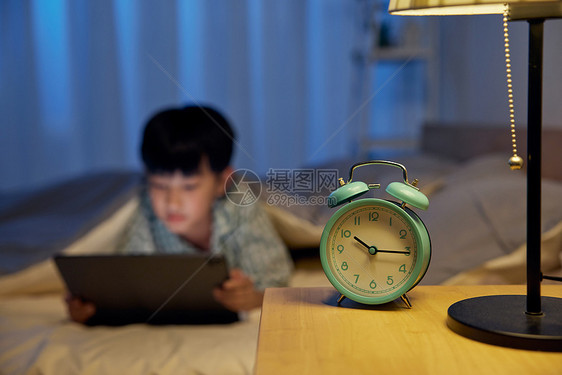 床上玩平板电脑的小男孩图片