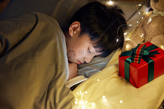熟睡的男孩枕边放着礼物盒图片