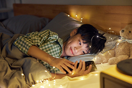 躺在床上看手机的男孩图片