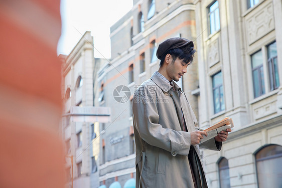 穿风衣手拿报纸的青年男性图片