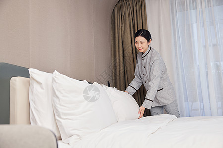 整理客房床铺的酒店服务员图片