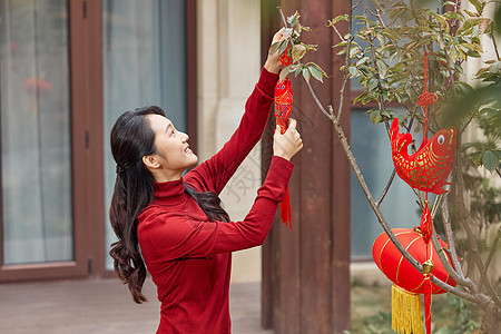 在树上挂新年装饰的女性图片