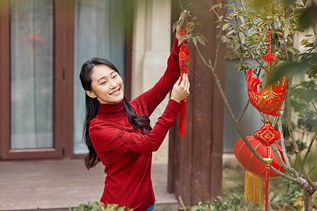 在树上挂新年装饰的女性图片