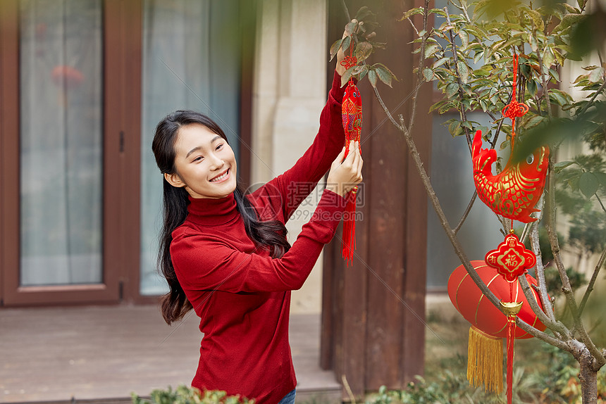 在树上挂新年装饰的女性图片