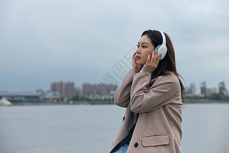 在江边带着耳机伤感情绪的年轻女性高清图片