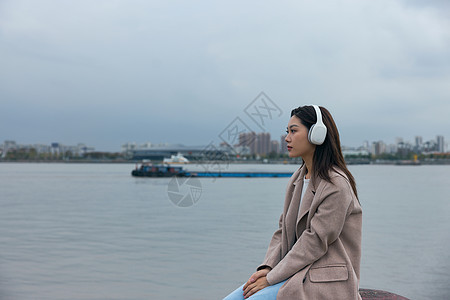 青年女性在江边带着耳机伤感情绪图片