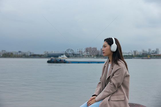 青年女性在江边带着耳机伤感情绪图片