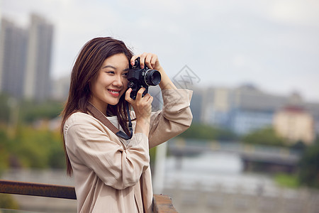 年轻女性天台拿着相机拍照图片