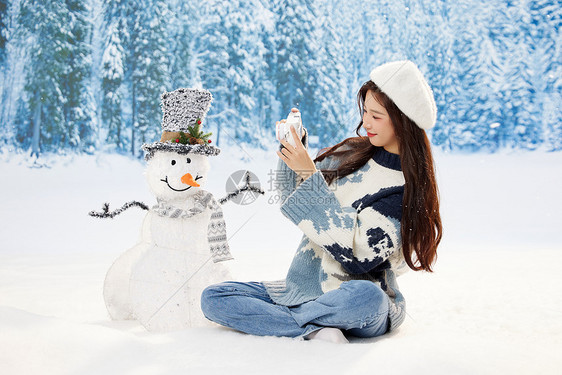 雪地里使用相机的可爱女孩图片