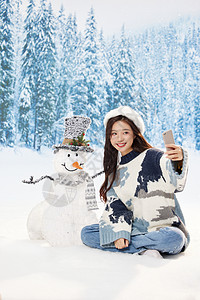 冬日雪地里的甜美女孩与雪人互动自拍图片