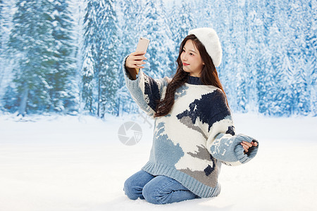 雪地里的美女使用手机自拍背景图片