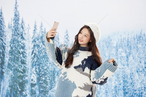 雪地里的美女使用手机自拍图片