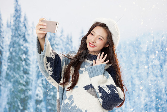 雪地里的甜美美女使用手机自拍图片