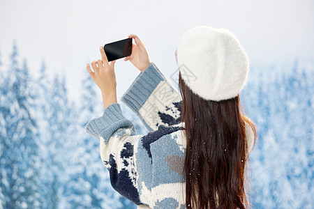 雪地里的美女使用手机自拍背影图片