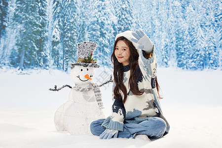 与雪人互动的冬日甜美女孩图片