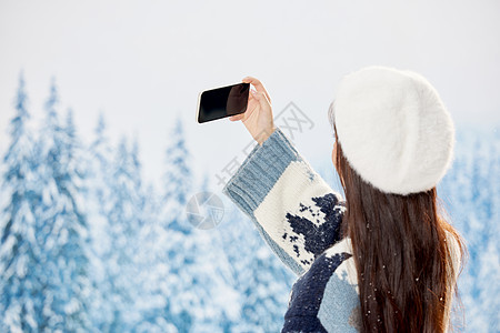雪地里的美女使用手机自拍背影图片