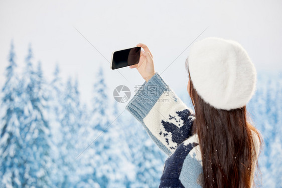 雪地里的美女使用手机自拍背影图片