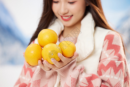 手捧水果可爱的冬日女孩手捧橘子特写背景