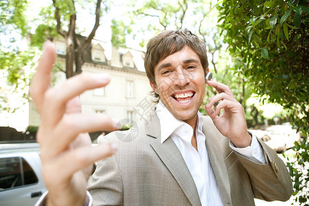 富有气势的年轻商人使用耳机设备和活泼的手机交谈图片