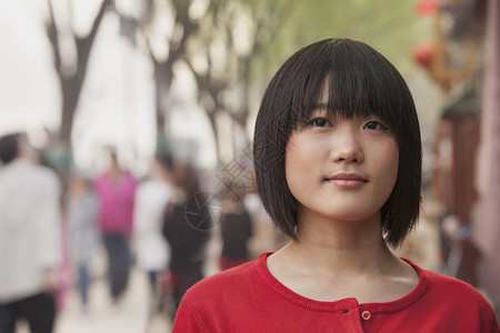 年轻女子微笑着看公园里的相机图片