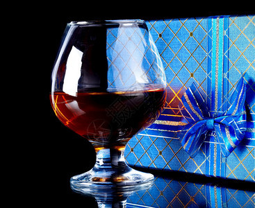 玻璃与酒精和一份礼物酒和礼品盒带弓的盒子和带图片