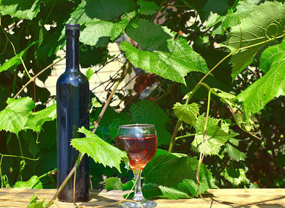 黑酒瓶和葡萄酒杯在木板上用红酒摊图片
