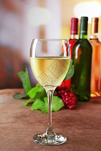 白葡萄酒杯木桌上含彩色瓶子的白葡萄酒图片
