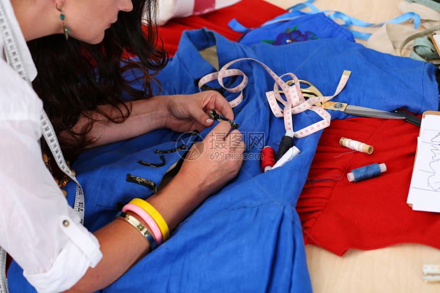 女时装设计师用针线缝制蓝色复古风格连衣裙的配饰在车间概念中创造服装服装缝纫和修理服图片